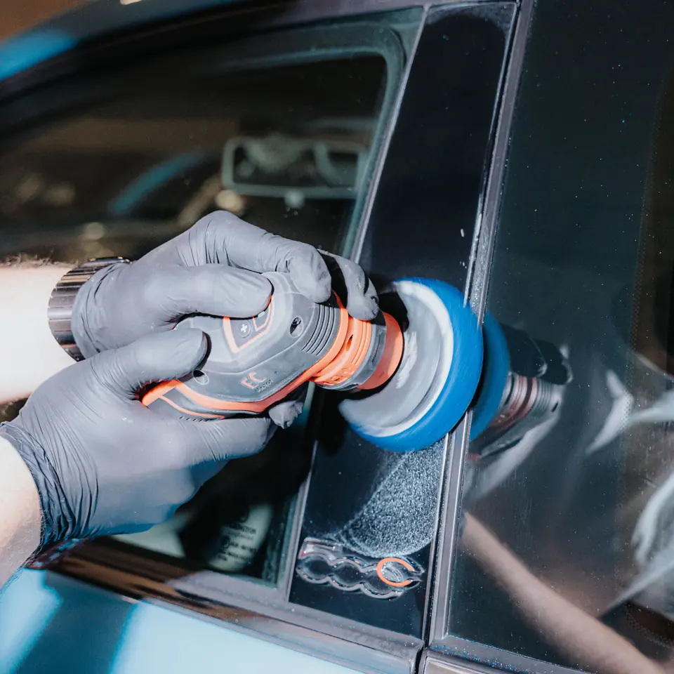 Lackaufbereitung mit der Poliermaschine an einem hellblauen Kleinwagen – Detailaufnahme